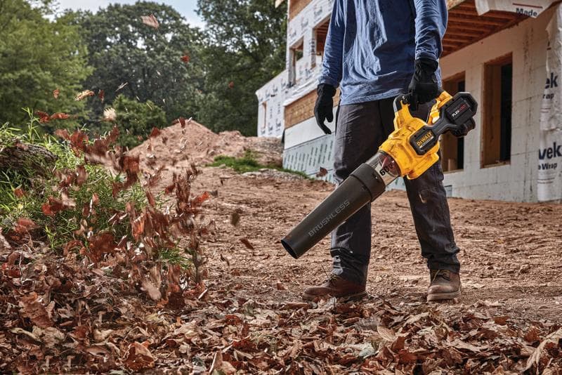 FLEXVOLT Brushless Cordless Handheld Axial Blower being used to clear leaves off  ground