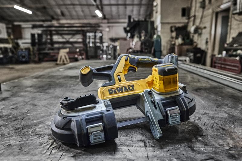 DEWALT cordless band saw placed on a metal workbench in a workshop setting.