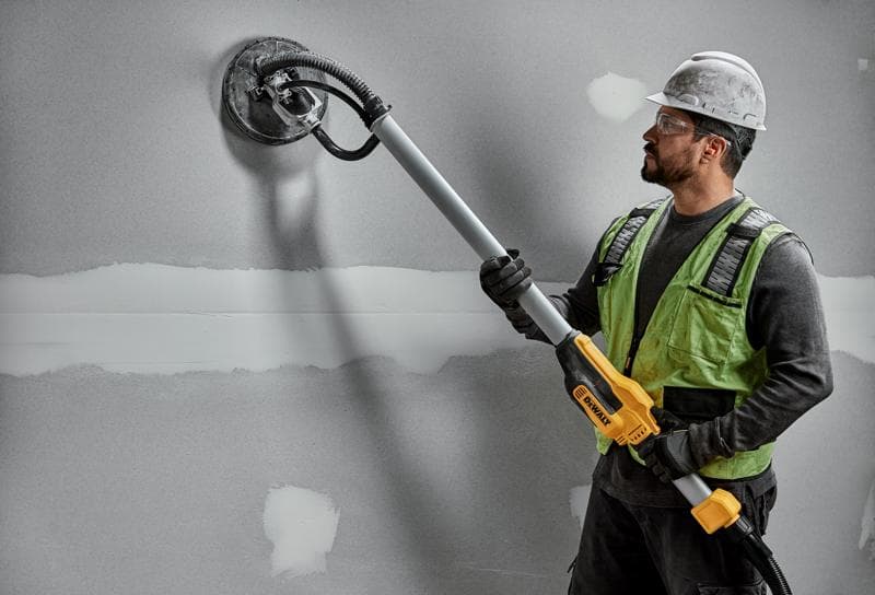 Worker uses DEWALT DWE7800, DWE7800-QS wall sander on drywall. Photography product shown in action.