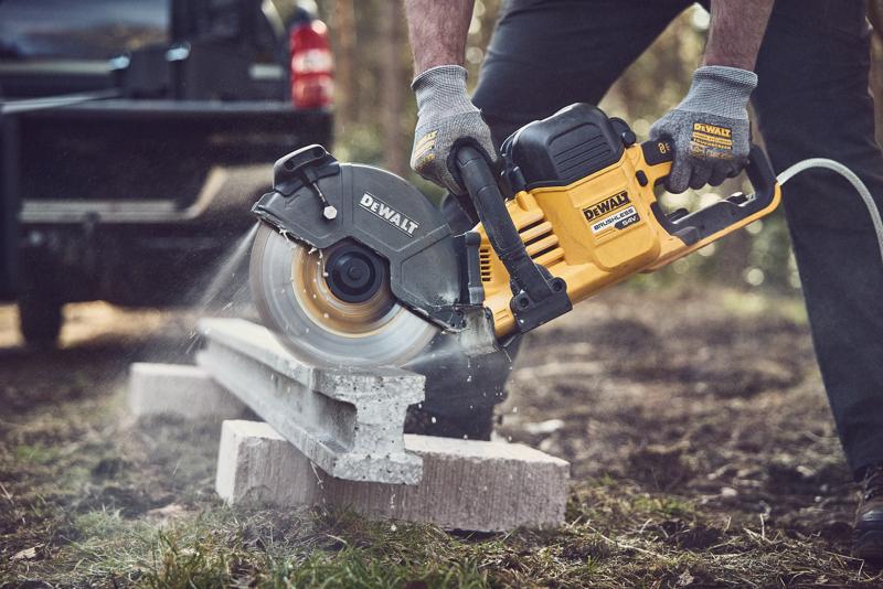 DEWALT power saw cutting concrete outdoors, operator wearing gloves for safety.